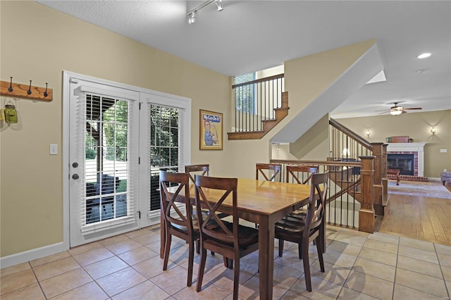 dining room with ceiling fan, a brick fireplace, and light hardwood / wood-style floors