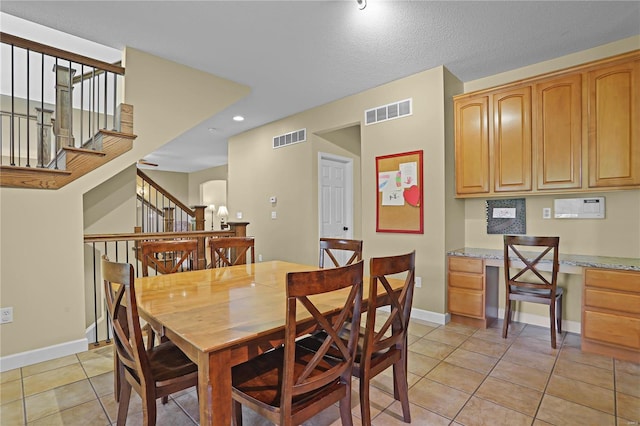 dining space featuring built in desk, a textured ceiling, and light tile patterned flooring