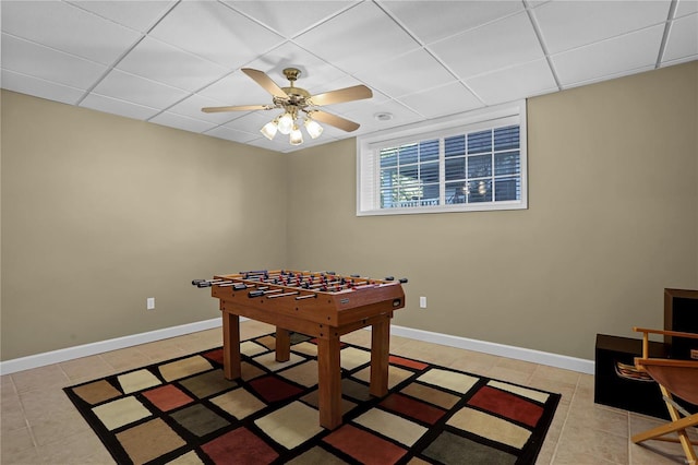 recreation room featuring a paneled ceiling, light tile patterned floors, and ceiling fan