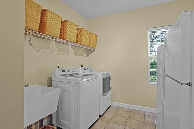 clothes washing area featuring washing machine and clothes dryer, light tile patterned floors, and sink