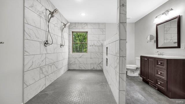 bathroom featuring tiled shower, vanity, and toilet