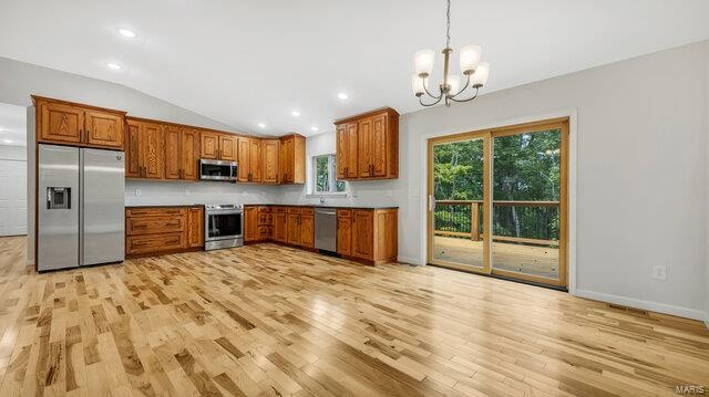 kitchen with light hardwood / wood-style floors, vaulted ceiling, stainless steel appliances, decorative light fixtures, and a chandelier