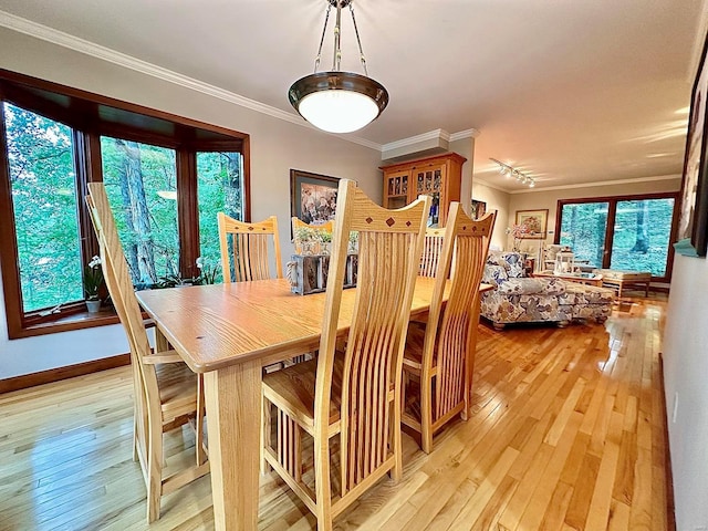 dining space with light wood-type flooring and crown molding