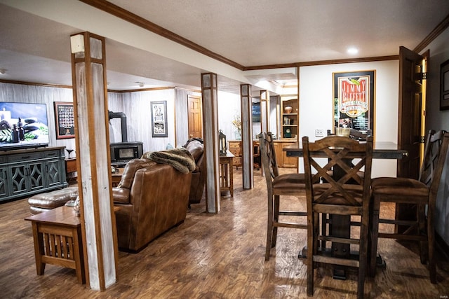 dining room featuring ornamental molding, a wood stove, a textured ceiling, wooden walls, and dark hardwood / wood-style floors