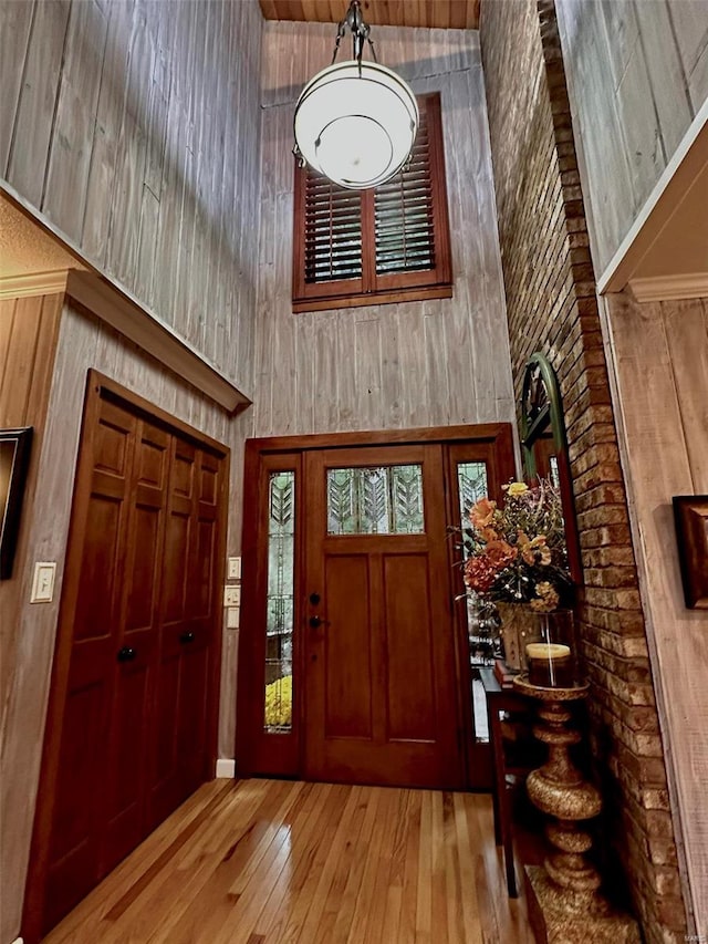 entryway featuring light hardwood / wood-style floors, a high ceiling, and wood walls