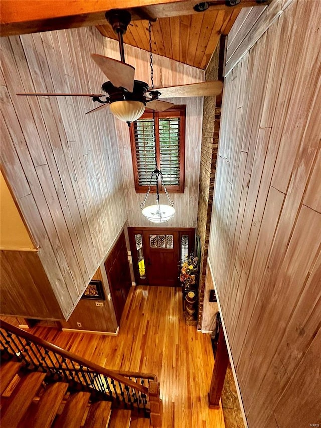 hall featuring wooden ceiling, vaulted ceiling with beams, wooden walls, and hardwood / wood-style floors