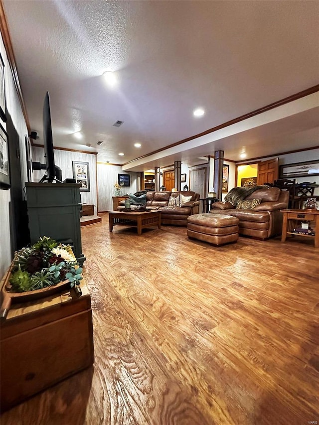 living room with a textured ceiling, crown molding, a fireplace, and hardwood / wood-style flooring