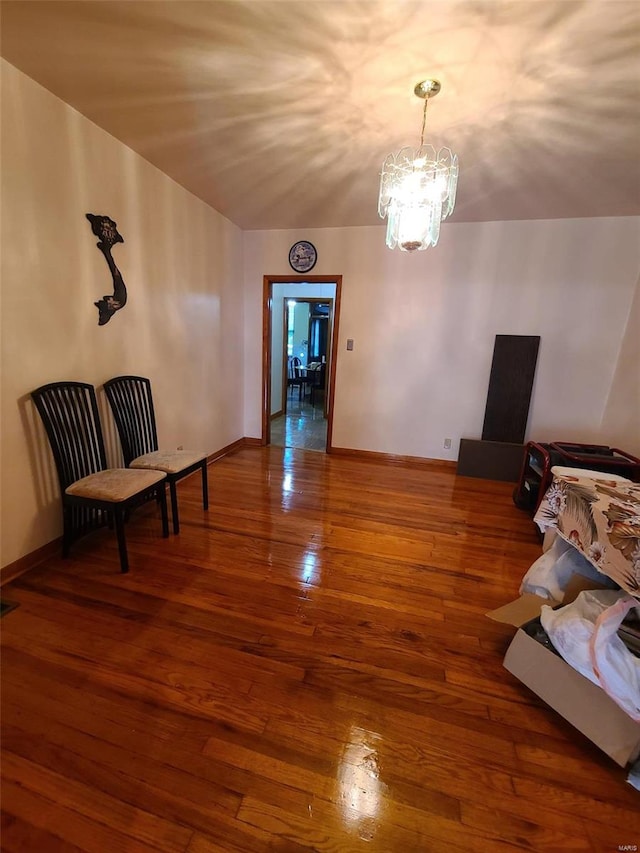 living area featuring lofted ceiling, a chandelier, and hardwood / wood-style floors