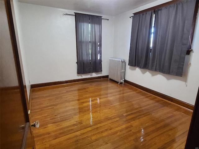 unfurnished room featuring wood-type flooring and radiator