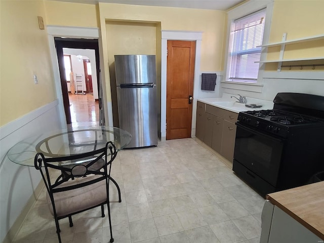 kitchen with gas stove, stainless steel fridge, and sink