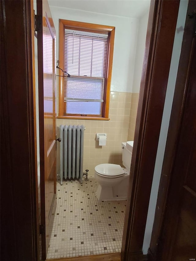 bathroom featuring tile walls, tile patterned floors, toilet, and radiator