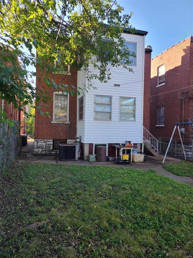 rear view of property featuring cooling unit, a lawn, and a patio area