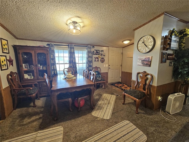 dining space with a textured ceiling, ornamental molding, wood walls, and dark carpet