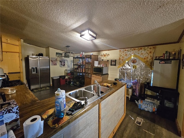 kitchen with a textured ceiling, sink, dark wood-type flooring, and stainless steel appliances