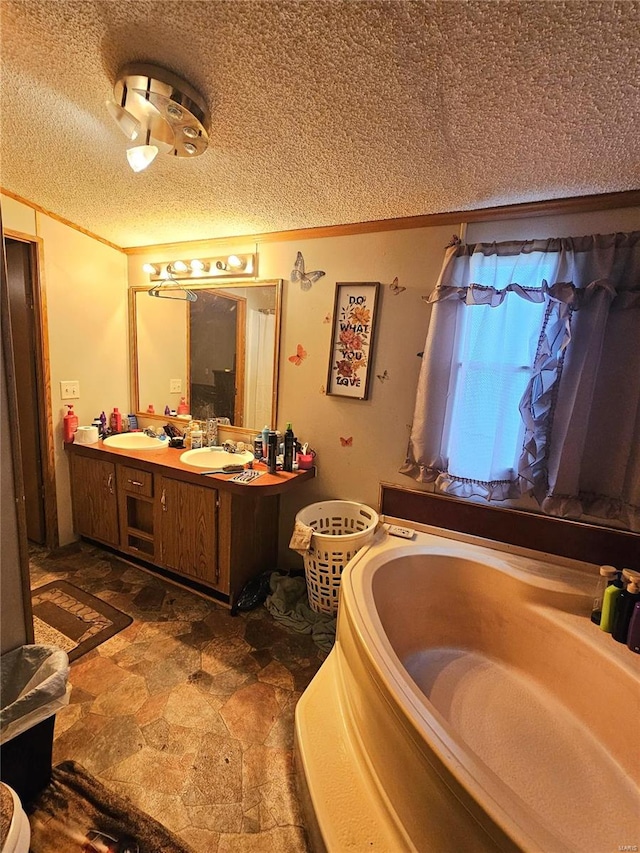 bathroom with vanity, a textured ceiling, and a tub