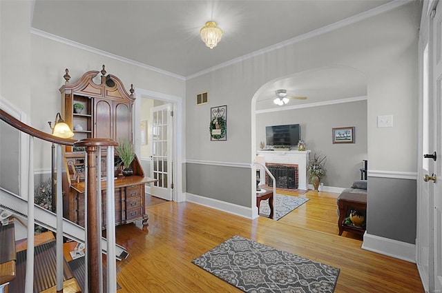 interior space with ceiling fan, hardwood / wood-style flooring, crown molding, and a brick fireplace