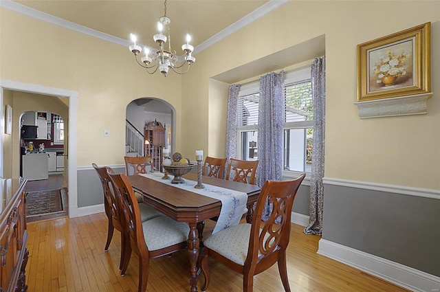 dining space with ornamental molding, an inviting chandelier, and light wood-type flooring