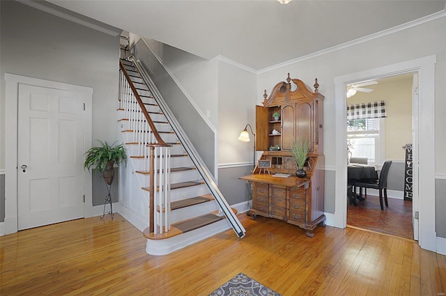 stairs with ceiling fan, crown molding, and hardwood / wood-style floors