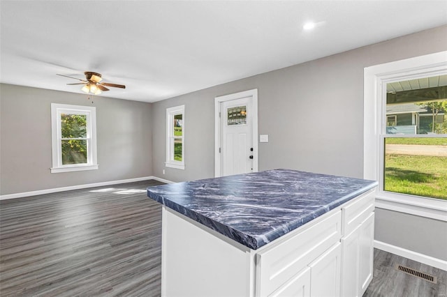 kitchen featuring ceiling fan, dark wood-type flooring, white cabinetry, and a kitchen island