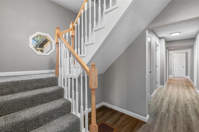 staircase featuring wood-type flooring and lofted ceiling