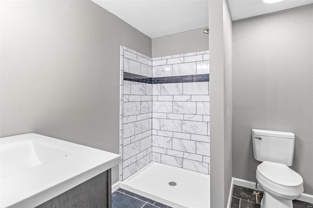 bathroom with a tile shower, vanity, and toilet