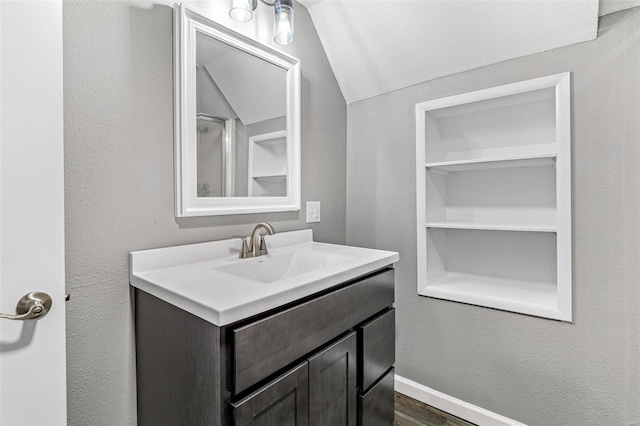 bathroom with lofted ceiling, hardwood / wood-style flooring, and vanity