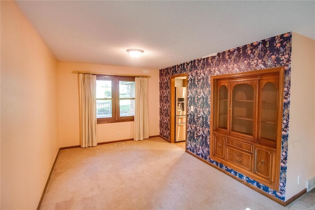 carpeted spare room with a textured ceiling