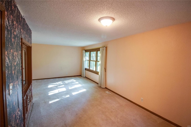 carpeted empty room featuring a textured ceiling