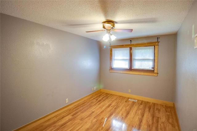 empty room with a textured ceiling, hardwood / wood-style floors, and ceiling fan