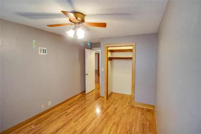 unfurnished bedroom with ceiling fan, a textured ceiling, light wood-type flooring, and a closet