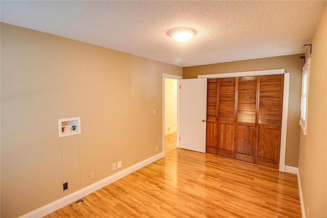 unfurnished bedroom with light wood-type flooring, a textured ceiling, and a closet