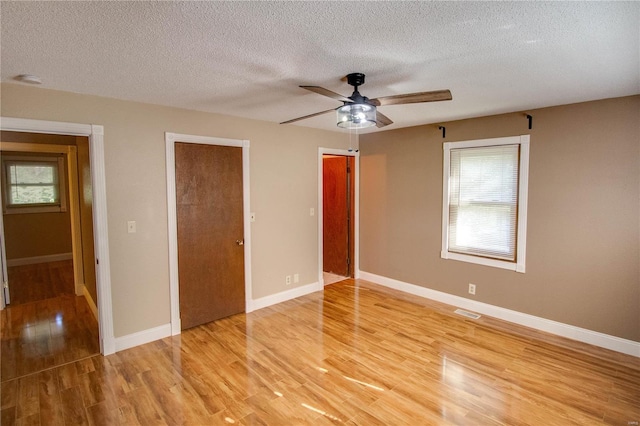 unfurnished bedroom with light hardwood / wood-style floors, multiple windows, and ceiling fan