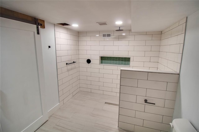 bathroom featuring a tile shower, tile walls, and toilet