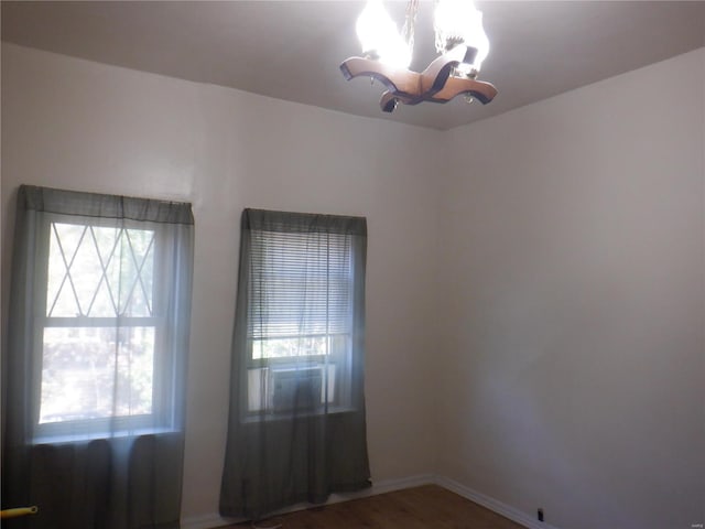 unfurnished room featuring a notable chandelier and wood-type flooring