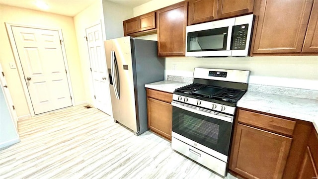 kitchen with light hardwood / wood-style floors and appliances with stainless steel finishes