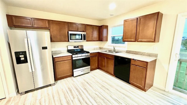 kitchen featuring appliances with stainless steel finishes, sink, and light hardwood / wood-style flooring