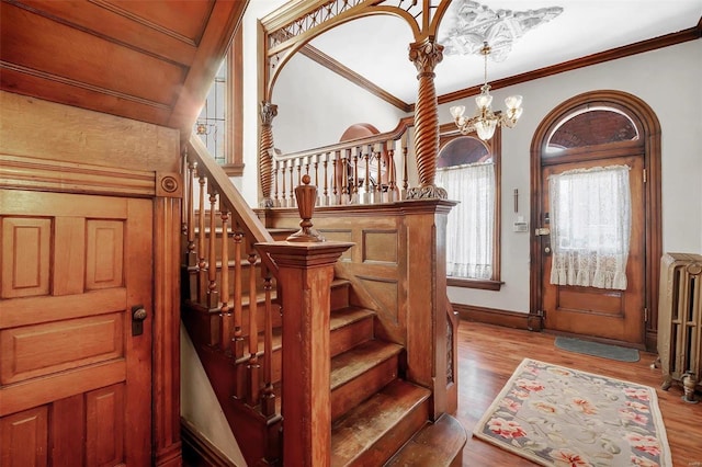 entryway featuring radiator heating unit, light hardwood / wood-style floors, ornamental molding, and a notable chandelier