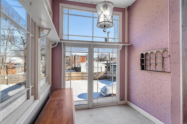 doorway featuring carpet flooring, a towering ceiling, and brick wall