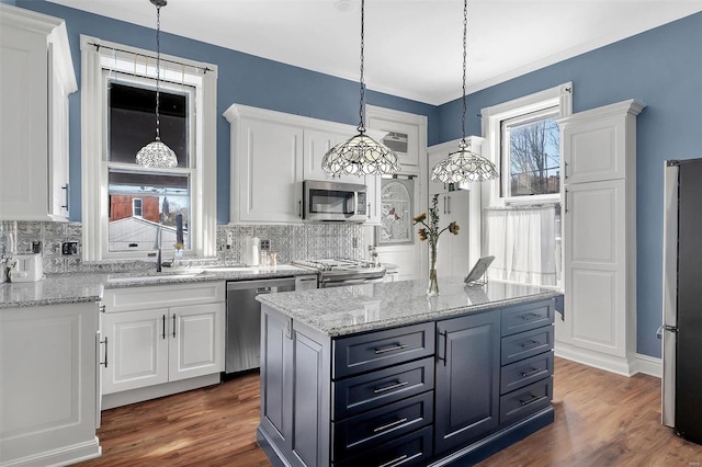 kitchen with a center island, sink, stainless steel appliances, pendant lighting, and white cabinets