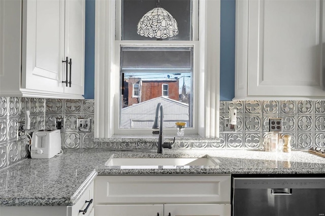 kitchen featuring light stone countertops, white cabinetry, sink, stainless steel dishwasher, and decorative backsplash