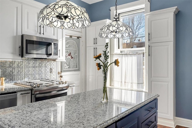 kitchen with light stone countertops, appliances with stainless steel finishes, tasteful backsplash, and white cabinetry