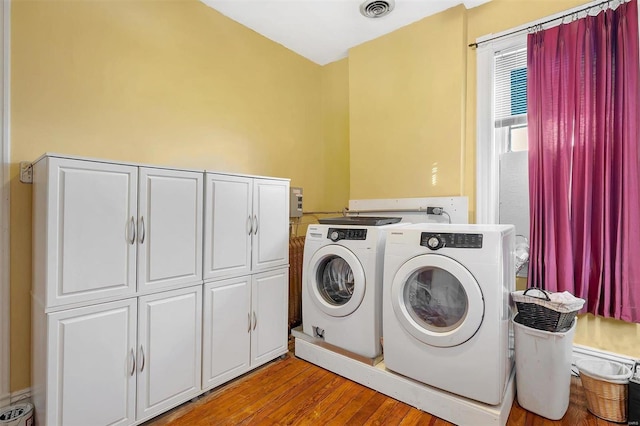 laundry area with washer and dryer, cabinets, and light wood-type flooring