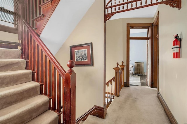 stairway with carpet flooring, plenty of natural light, and radiator