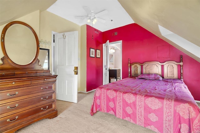 carpeted bedroom with ensuite bath, ceiling fan, and vaulted ceiling with skylight