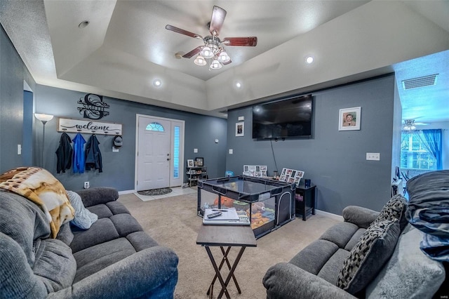 carpeted living room featuring ceiling fan and a raised ceiling