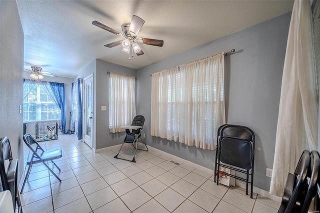 sitting room with ceiling fan, light tile patterned floors, and a textured ceiling