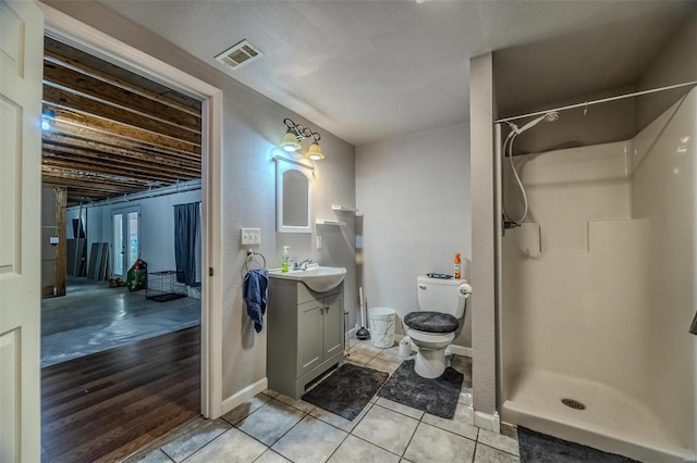 bathroom featuring a textured ceiling, hardwood / wood-style flooring, a shower, vanity, and toilet