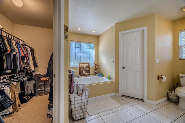 bathroom featuring plenty of natural light, toilet, a washtub, and tile patterned floors