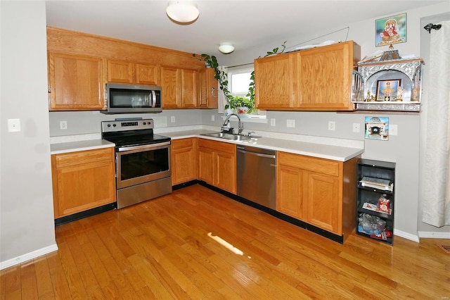 kitchen featuring light wood-type flooring, appliances with stainless steel finishes, and sink