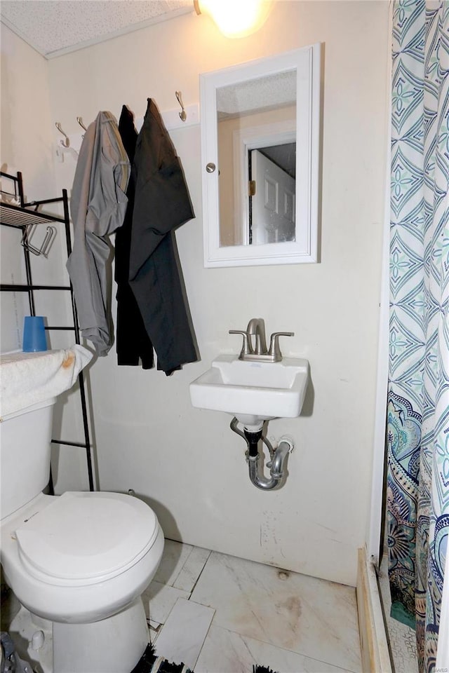 bathroom with a textured ceiling, sink, toilet, and a shower with shower curtain